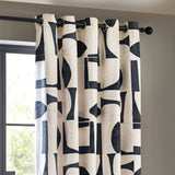 Carro Abstract Lined Eyelet Curtains in Dusk, cream cotton fabric printed with bold black geometric shapes, hung on a black metal pole beside a window with a matte black eyelet ring detail.