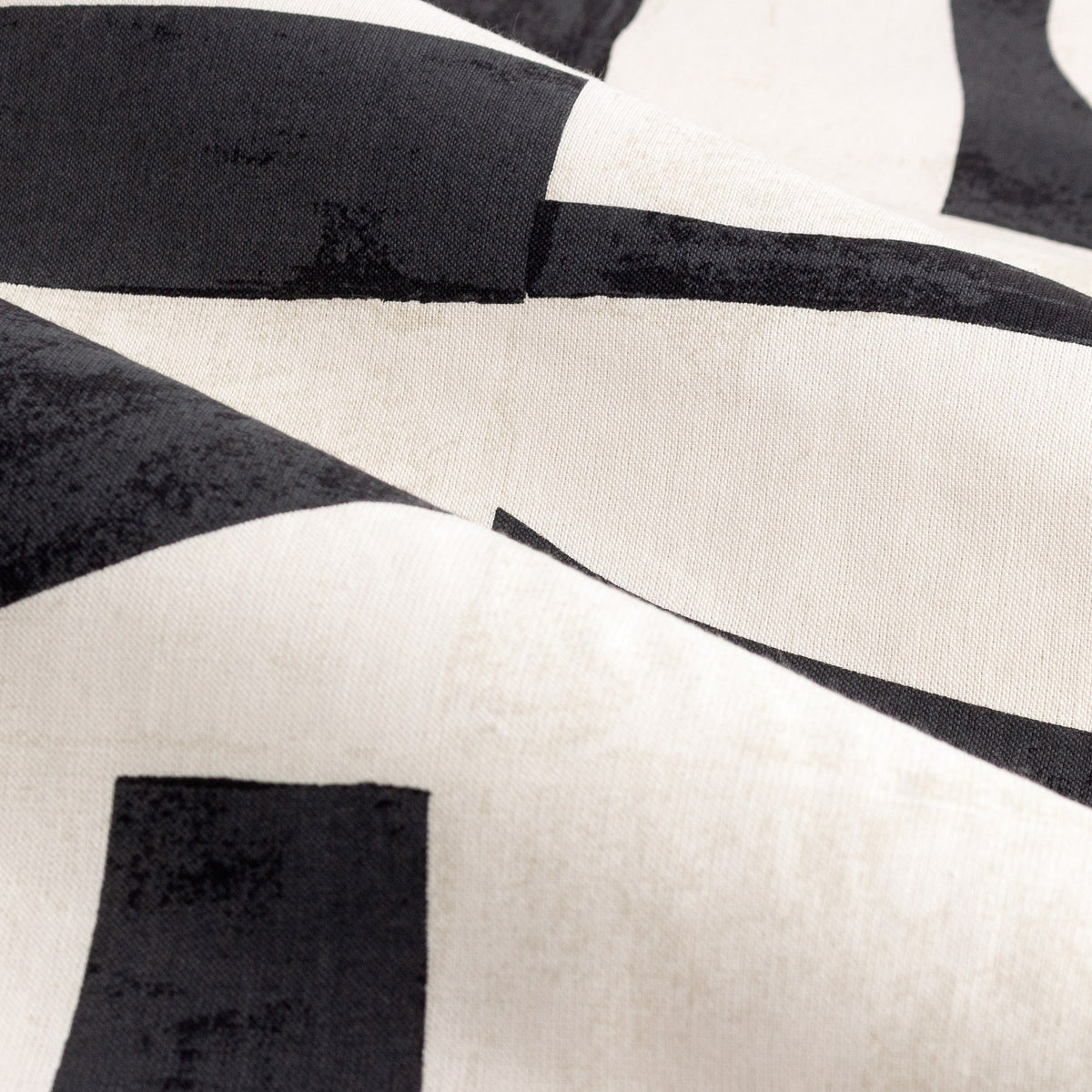 Close-up of Carro Abstract Lined Eyelet Curtains fabric, showing bold black geometric shapes and bars printed on a cream cotton half-panama weave.