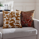 Caval Velvet Chenille Cushion in Bronze with abstract cream jacquard pattern, styled on a grey sofa beside a maze-patterned brown cushion.