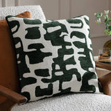 Caval Velvet Chenille Cushion in Ivy Green, square with an abstract jacquard pattern in dark green on off-white, textured chenille and boucle finish, shown on a light armchair.