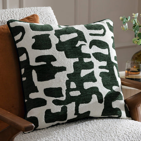 Caval Velvet Chenille Cushion in Ivy Green, square with an abstract jacquard pattern in dark green on off-white, textured chenille and boucle finish, shown on a light armchair.