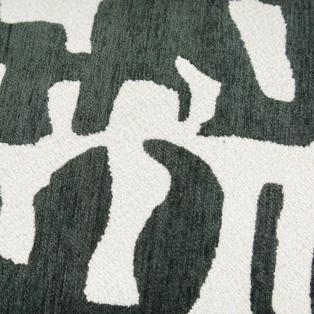 Close-up of the Caval Velvet Chenille Cushion in Ivy Green, showing an abstract jacquard pattern with dark green shapes on an off-white ground, contrasting boucle and chenille textures.