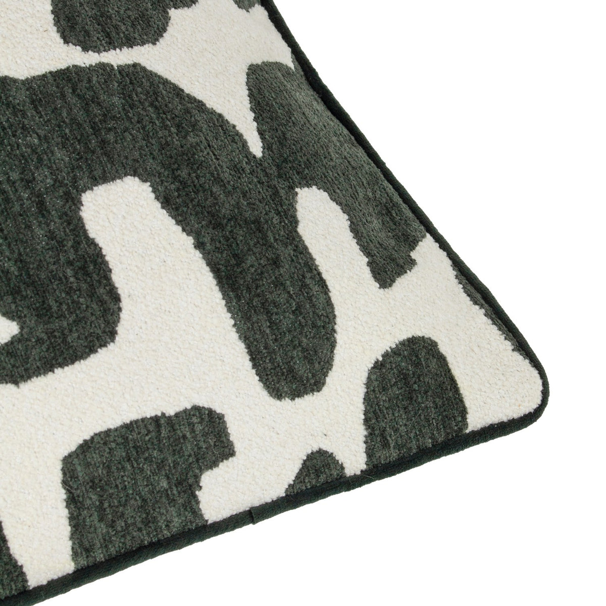 Close-up corner detail of the Caval Velvet Chenille Cushion in Ivy Green, showing a bold abstract pattern in dark green chenille pile against an off-white ground, with green piped edge trim.