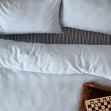Club Checkerboard Plain Check Duvet Cover Set in Blueberry, pale blue waffle-textured bedding with pillowcases and black striped trim, styled with a checkers board on a bed.