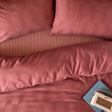 Club Checkerboard Duvet Cover Set in raspberry pink, showing a waffle-textured check pattern on pillowcases and striped cotton-blend cover, styled with a radio and book.