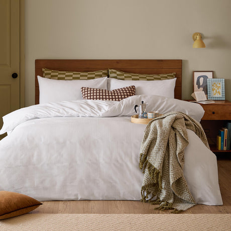 Club Checkerboard duvet cover set in white waffle-textured cotton-polyester blend, styled on a bed with checked pillowcases, a patterned cushion, and an olive throw in a bedroom setting.