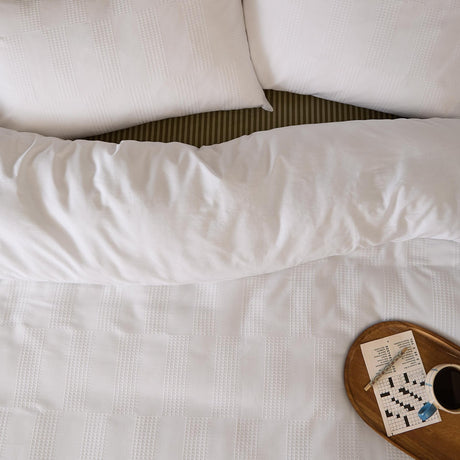 Club Checkerboard duvet cover set in white with waffle-textured checkerboard pattern, styled on a bed with matching pillowcases beside a breakfast tray.