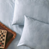 Club Checkerboard cotton blend pillowcase pair in Blueberry, shown on a bed with woven waffle-textured checkerboard pattern and smooth reverse, styled beside a checkers board.