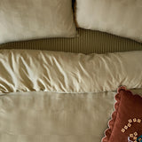 Club Checkerboard Check Cotton Blend Pillowcase Pair in green, shown on a bed with woven waffle-textured squares and a striped duvet beneath.