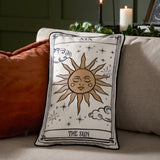 Celestial Stories Linen Cotton Cushion in cream and black, embroidered tarot-style Sun card design with sun face, stars and clouds, shown on a sofa.