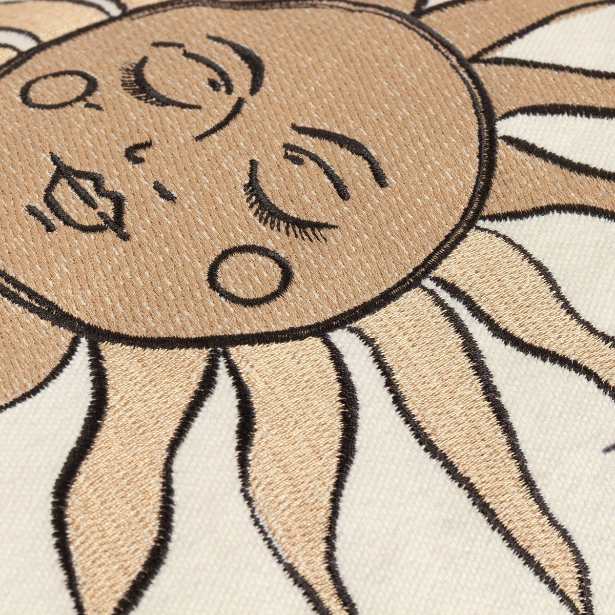 Close-up of the Celestial Stories Linen Cotton Cushion in Linen/Black, showing embroidered sun face detail with closed eyes, rays and raised black outline stitching on cream fabric.