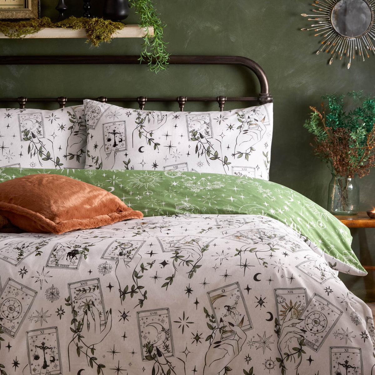 Celestial Stories reversible duvet cover set on a bed, cream side shown with tarot card, hand, star and vine print, paired with green pillowcases and reverse fabric in a green-walled bedroom.