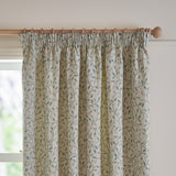 Cervino Jacquard Pencil Pleat Curtains in duck egg, cream fabric with woven trailing leaf pattern in blue, sage and tan, hung on a wooden pole near a window.