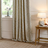 Cervino Jacquard Pencil Pleat Curtains in Duck Egg, cream fabric with woven trailing leaf pattern in blue, sage and tan, shown pooling by a window in a living room setting.