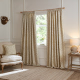 Cervino Jacquard Pencil Pleat Curtains in Lichen with a cream ground and leaf pattern in green and taupe, shown pencil-pleated on a wooden pole in a living room setting.