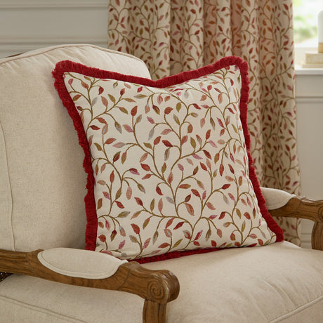 Cervino Jacquard Cotton Blend Cushion in Rednut, with a red fringed edge and cream fabric featuring a woven trailing leaf pattern in red, rust and pink, shown on an armchair.