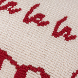 Close-up of the Candy Fa La La cushion showing red hand-tufted "Fa La" lettering on a cream cotton-polyester looped pile face.