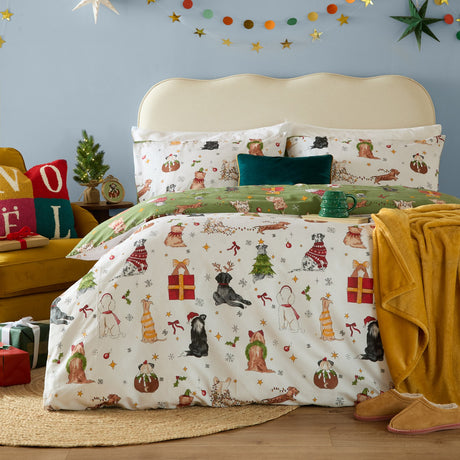 Christmas Pawty reversible cotton-blend duvet cover set in cream and green, printed with festive dogs, gifts and bows, styled on a bed with matching pillowcases.
