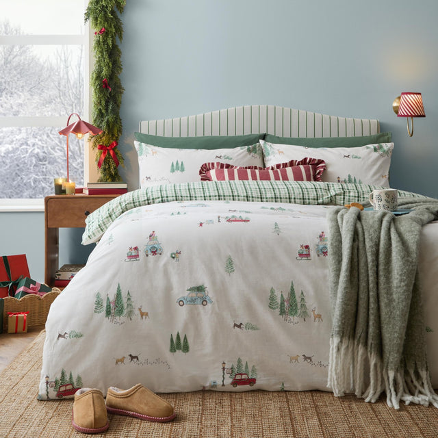 Christmas Tree Lane Check Duvet Cover Set in natural/sage, cotton bedding with a printed winter scene of cars, sleds and pine trees, styled on a bed with checked pillows in a festive bedroom.