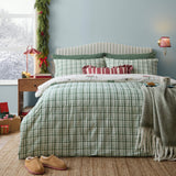 Christmas Tree Lane reversible duvet cover set in natural/sage check cotton, dressed on a bed with matching pillowcases and a red striped cushion in a pale blue bedroom.