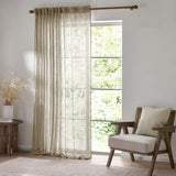 Cirrus Plain Linen Curtain Panel in beige sheer woven polyester, shown hanging from a wooden pole beside a window in a living room with an armchair.