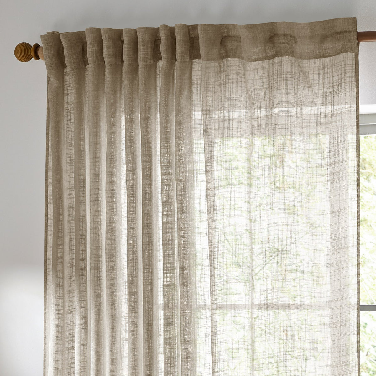 Cirrus Plain Linen Curtain Panel in beige sheer polyester with tab-top heading, hung on a wooden curtain rod beside a window.