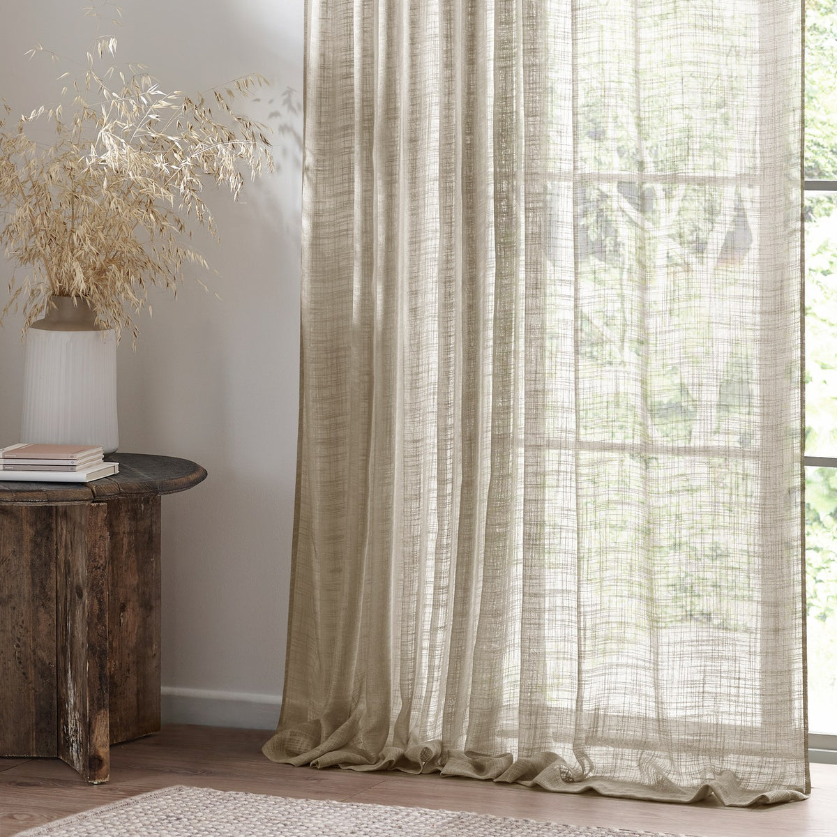 Cirrus Plain Linen Curtain Panel in beige, sheer woven polyester with a textured weave, shown hanging by a window in a living room setting.