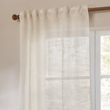 Cirrus Plain Polyester Curtain Panel in pearl cream, sheer woven fabric with tab-top heading on a wooden rod beside a window in a living room.