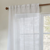 Cirrus Plain Polyester Curtain Panel in snow white, sheer woven fabric with tab-top heading on a wooden rod beside a window in a neutral room.
