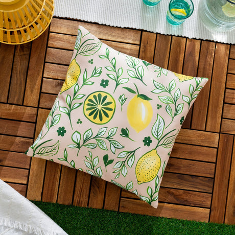 Square peach cushion with hand-painted lemon print, leafy vines and small flowers in green and yellow, shown on wooden outdoor decking.