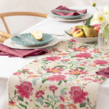 Claudia Floral Polyester Table Runner in Candy Red, cream base with pink and red floral print and green foliage, styled on a dining table with teal plates and pink napkins.