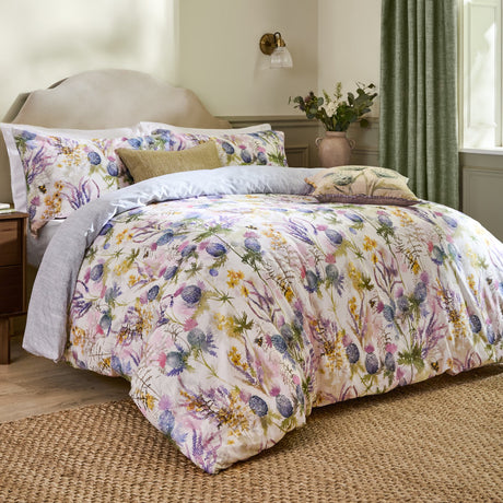 Cluaran Cotton Floral Duvet Cover Set in multi on a bed with matching pillowcases, featuring a watercolour thistle, lavender and floral print in a bedroom setting.