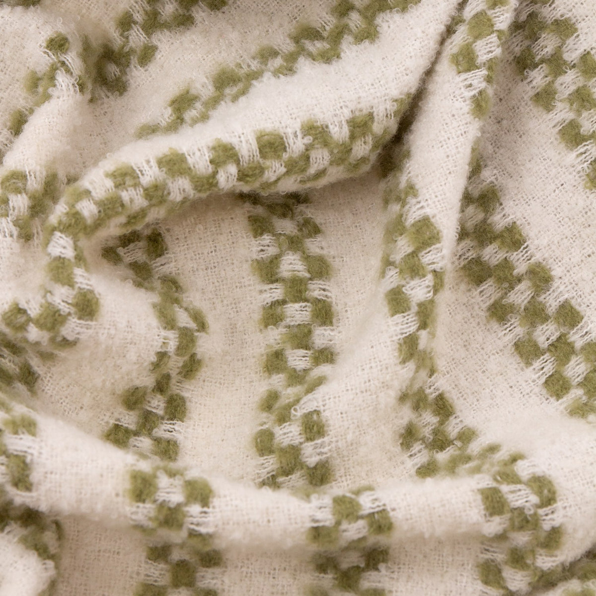Close-up of the Clyne Check Polyester Throw in olive, showing woven check-stripe bands in soft green on a cream ground with a textured, draped finish.