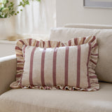 Connie Striped Linen Cushion in clay pink, a rectangular ruffled-edge cushion with pink and oatmeal stripes, shown styled on a beige sofa.
