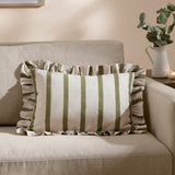 Connie Striped Linen Cushion in olive, a rectangular ruffle-edged cushion with green and oatmeal stripes, shown on a beige sofa in a living room.
