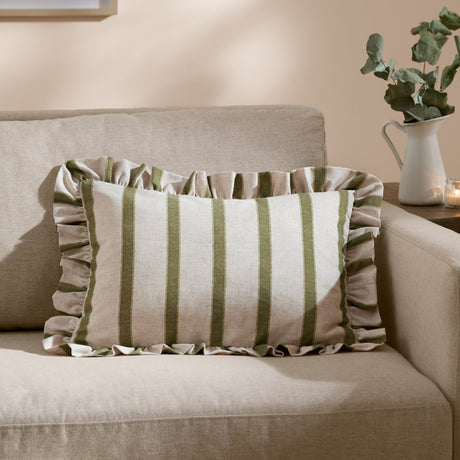 Connie Striped Linen Cushion in olive, a rectangular ruffle-edged cushion with green and oatmeal stripes, shown on a beige sofa in a living room.