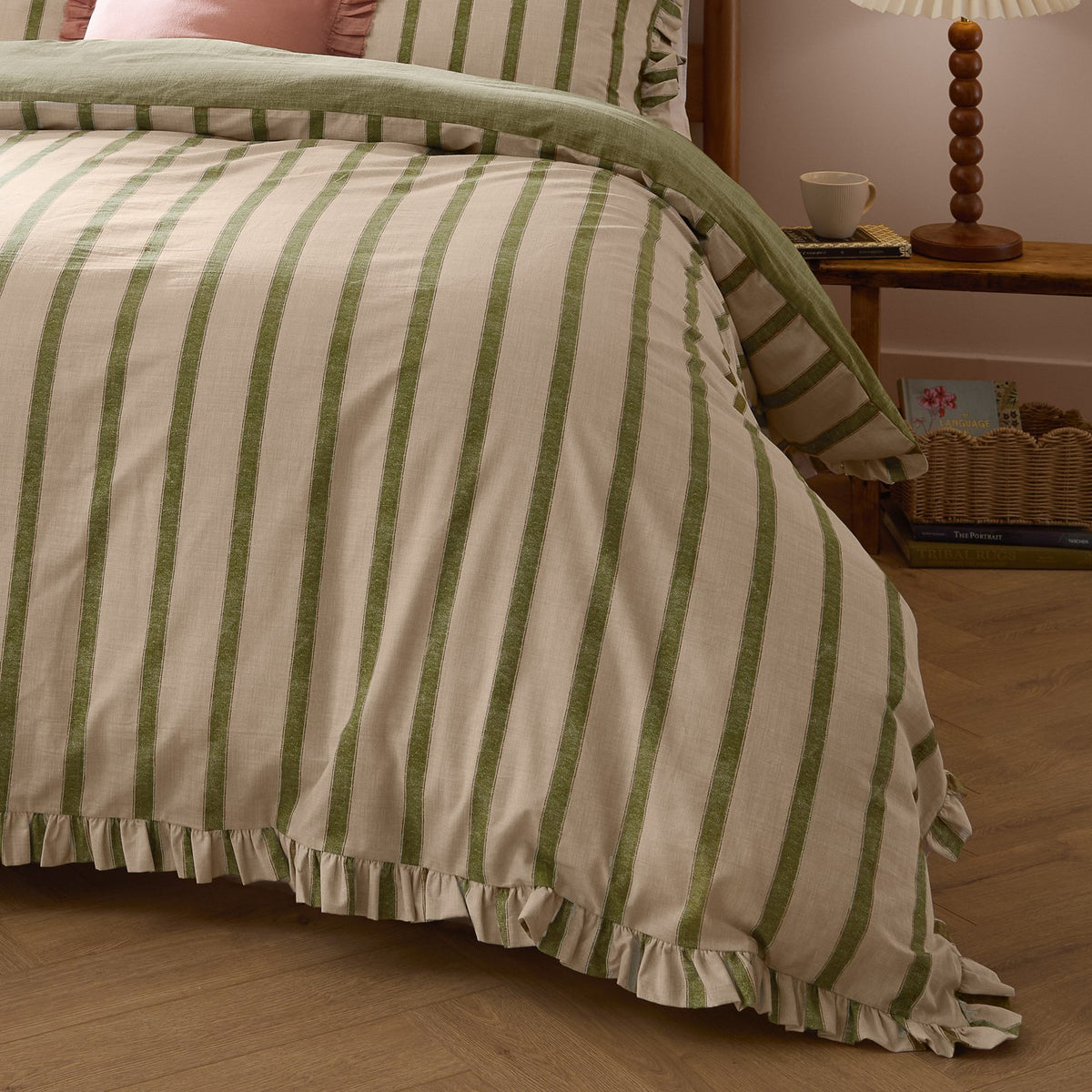 Connie Linen Plain Duvet Cover Set in Olive on a bed, showing broad olive-green stripes on natural cotton fabric with a ruffled edge trim, styled in a bedroom with a wooden side table.