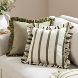 Connie Striped Linen Cushion in Moss, a square cushion with vertical moss green stripes on natural linen-look fabric and a frilled edge trim, shown on a sofa beside a plain olive ruffled cushion.