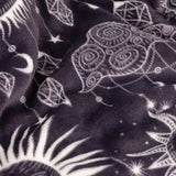 Constellation Printed Polyester Throw in charcoal, shown folded with cream celestial line-work of suns, moons, stars, eyes and faceted gems across the fabric.