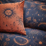 Constellation Printed Reversible Duvet Cover Set in Bronze/Navy, showing sun, moon and star motifs, styled with a bronze pillow against a matching navy polycotton duvet.