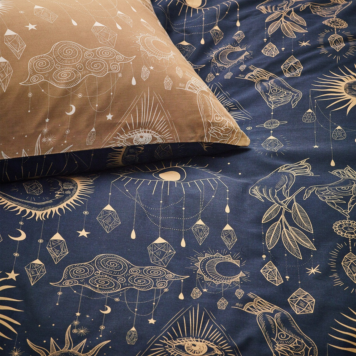 Constellation Printed Reversible Duvet Cover Set in Gold/Navy, showing celestial sun, moon and crystal line-art on navy bedding with matching caramel-gold pillowcase.