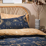 Constellation Printed Reversible Duvet Cover Set in Gold/Navy on a bed with rattan headboard, showing celestial sun, moon and star motifs on both navy and gold sides.