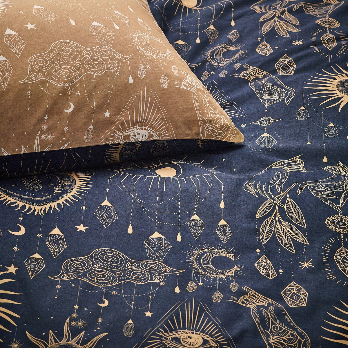 Constellation Printed Reversible Duvet Cover Set in gold and navy, showing celestial moon, sun and crystal motifs on the navy duvet and gold pillowcase.