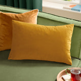 Contra Velvet Linen Cushion in mustard, an oblong velvet-fronted cushion shown on a green sofa alongside a matching square cushion.