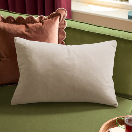 Contra Velvet Linen Cushion in natural, rectangular velvet-faced cushion shown on a green sofa alongside a scalloped rust-coloured velvet cushion.