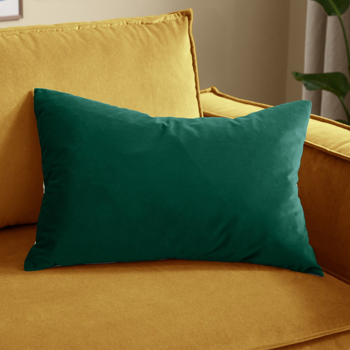 Contra Velvet Linen Cushion in teal, rectangular velvet cushion with plain finish, shown on a mustard yellow sofa.
