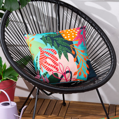Coralina Abstract Polyester Cushion in Multi, a square cushion with a bold tropical print in turquoise, coral, green and orange, shown on a black wicker chair.