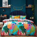 Coralina Jungle Floral Duvet Cover Set in multicoloured tropical print with pink, orange, green and navy leaf motifs, shown on a bed with matching pillowcases and a mustard cushion in a teal bedroom.