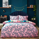 Coralina Jungle Floral Duvet Cover Set shown reversed, with a pink ground and navy branching leaf print, styled on a bed with matching pillowcases in a teal bedroom.
