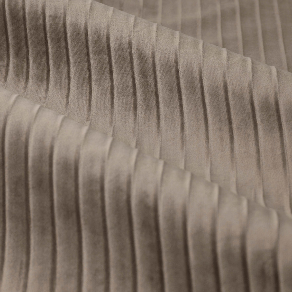 Close-up of Corinthian velvet eyelet curtain fabric in taupe, showing fine vertical micro-pleats that create a soft, light-catching ridged texture.